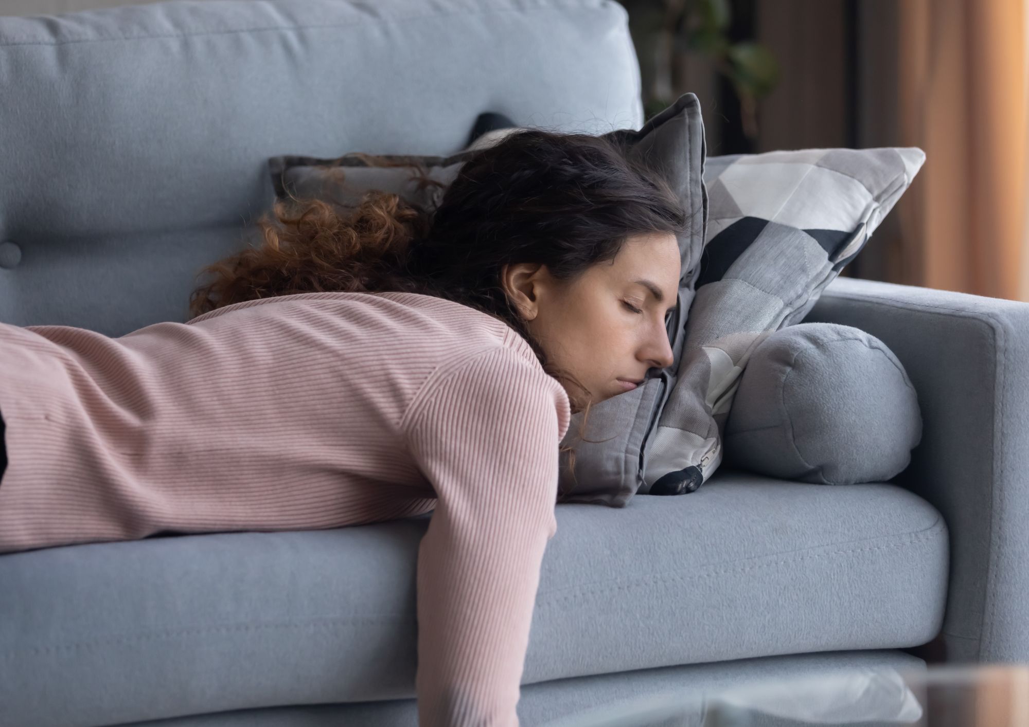 woman laid on sofa exhausted from sleep or hormonal issues