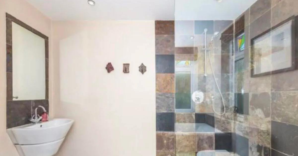 Completed bathroom refurbishment by CDI Contractors featuring a wall-mounted basin and glass-enclosed shower with multicoloured stone-effect tiles.