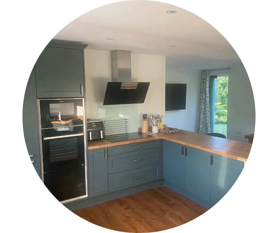 Green fitted kitchen with wooden worktops, integrated appliances and practical corner storage, installed by CDI Contractors.