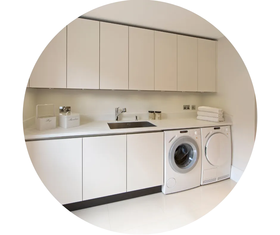 Modern utility room with fitted cupboards, sink, worktop, washing machine and tumble dryer for practical household storage and laundry.