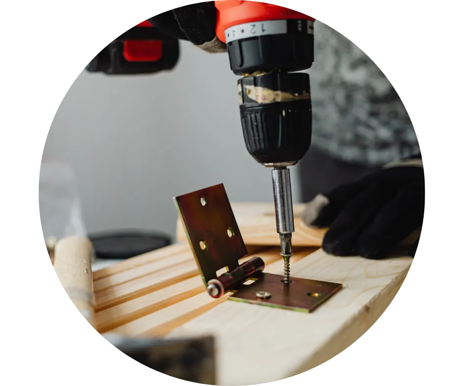 Close-up of a drill fixing a metal hinge to timber, illustrating carpentry and property maintenance services offered by CDI Contractors.