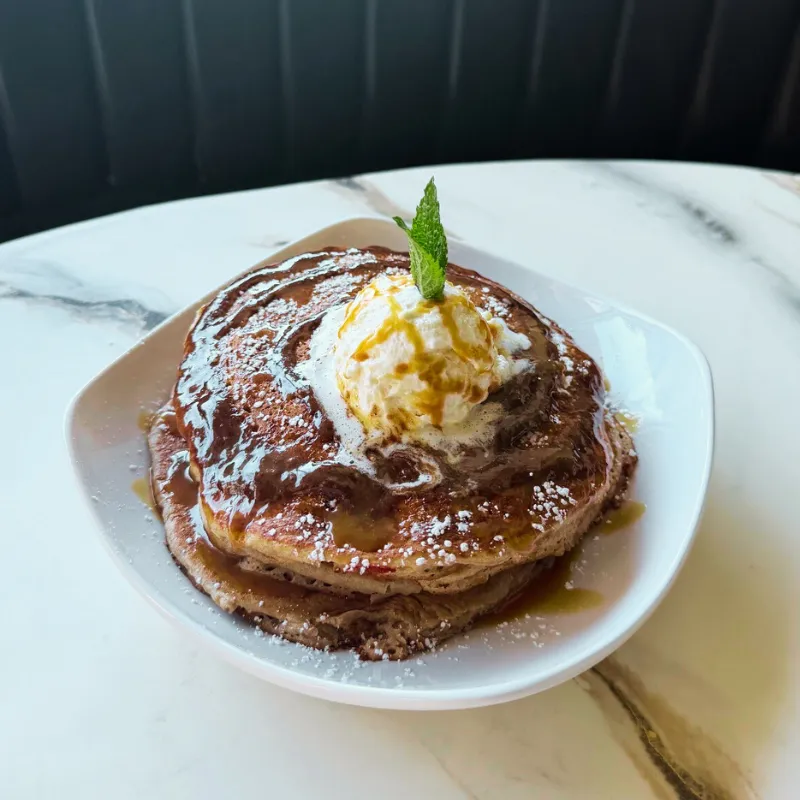 Churro pancakes with caramel drizzle and whipped cream topping.