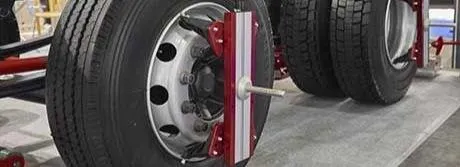 Technician inspecting heavy-duty wheel alignment sensors on a semi trailer