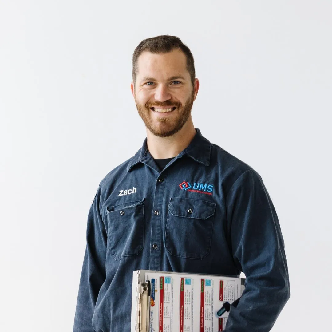 A man named Zachary Baldwin, wearing a blue shirt, holds a folder, representing his expertise as an HVAC Wizard.