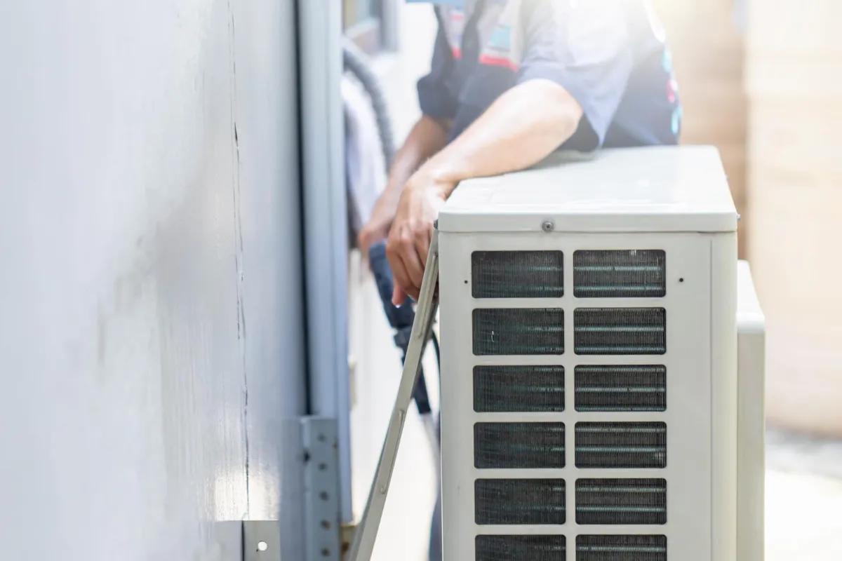 A man stands adjacent to an air conditioner, emphasizing the appliance's presence in a contemporary indoor space.