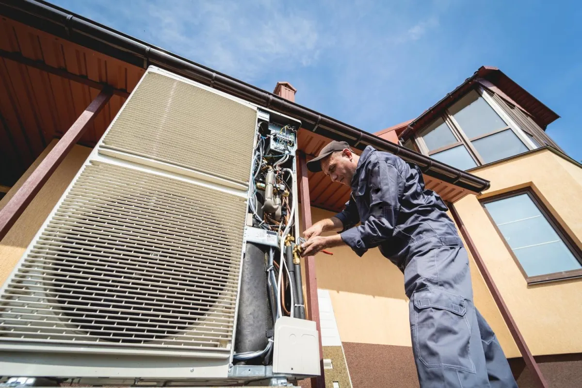 A man wearing a blue shirt is engaged in fixing an air conditioner.