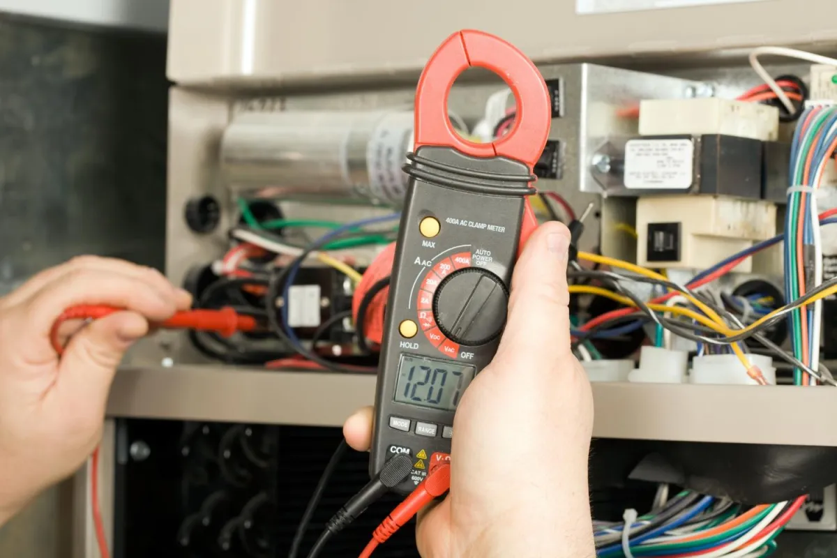 A technician uses a multimeter to measure the temperature of an air conditioner for maintenance and diagnostics.