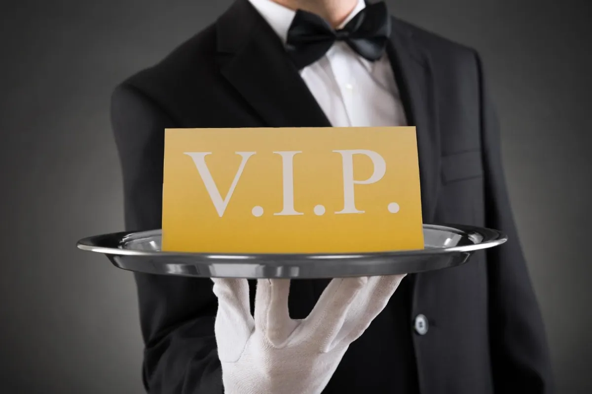 A waiter in a tuxedo elegantly holds a tray featuring a VIP sign, symbolizing premium service and exclusivity.