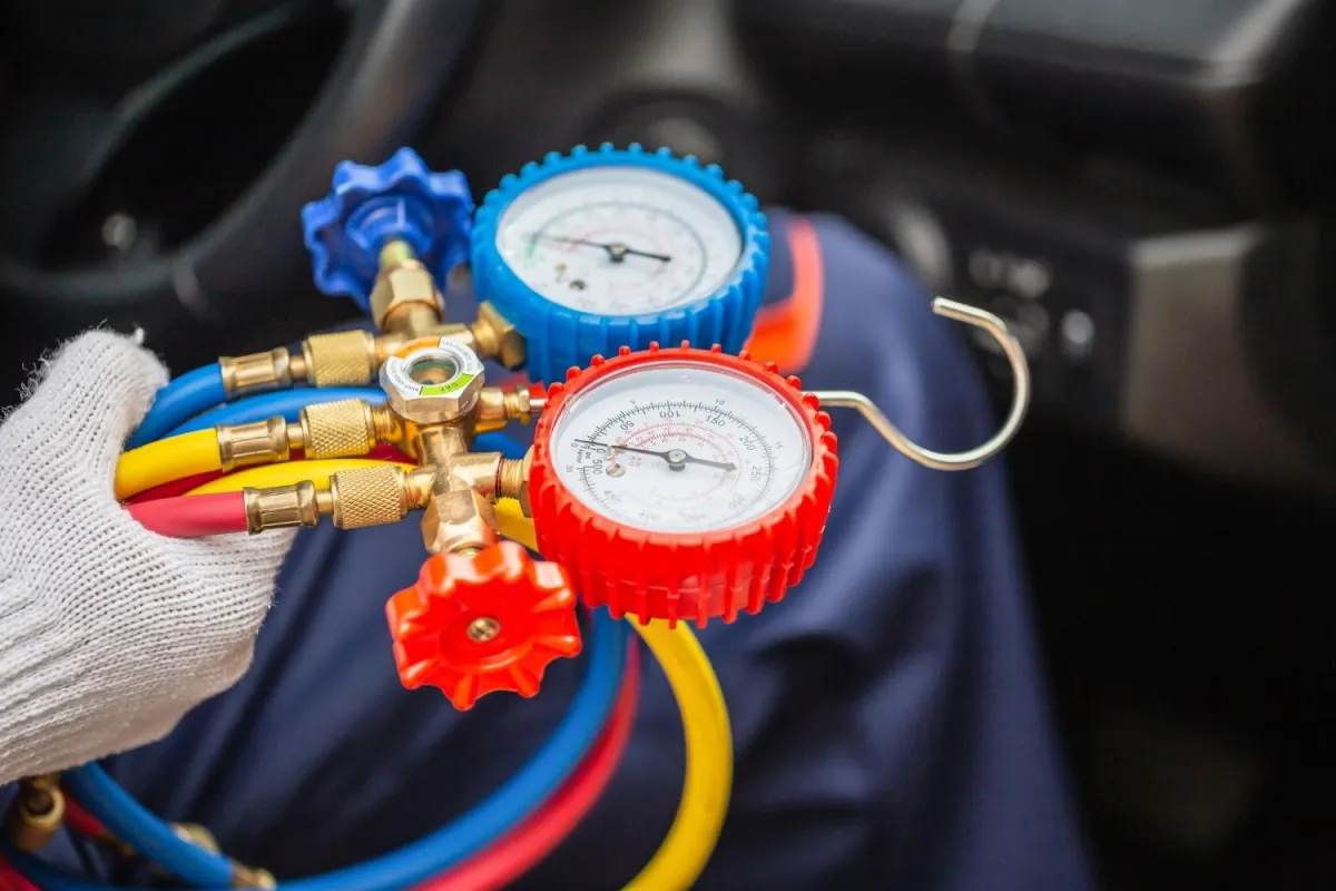 A person seated in a car, holding a gauge in their hand, focused on measuring or monitoring something important.