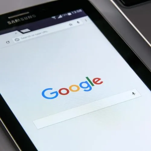 A close-up of a smartphone with the Google search engine visible, highlighting the search bar and displayed search results.