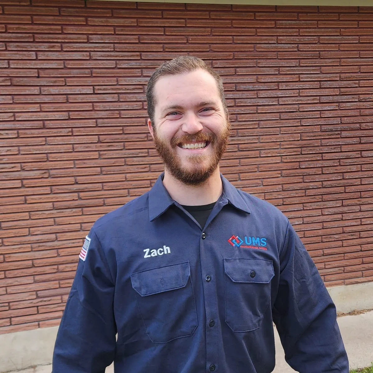 A smiling man in a blue shirt and blue jeans, representing Zachary Baldwin from Utah Heating and Air Conditioning Service.