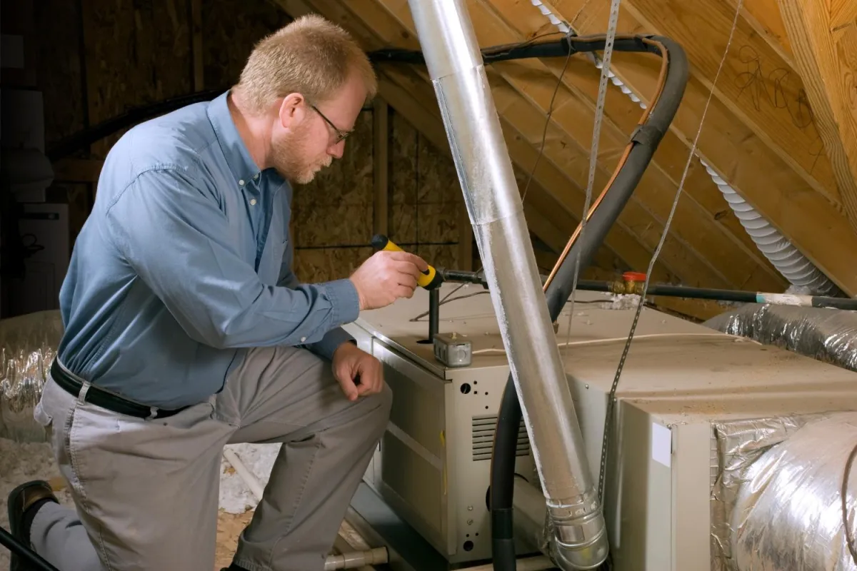 A technician is engaged in the maintenance of an air conditioner, using tools to ensure optimal performance and efficiency.