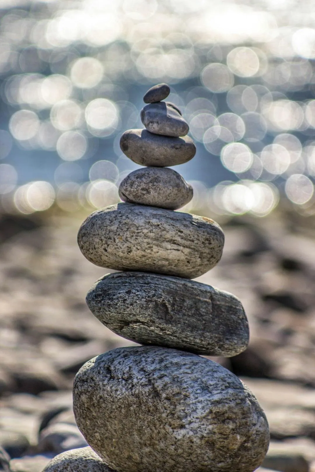 Rocks that are stacked on top of each other by the ocean blurred in the background, giving the common sense of a wellness center