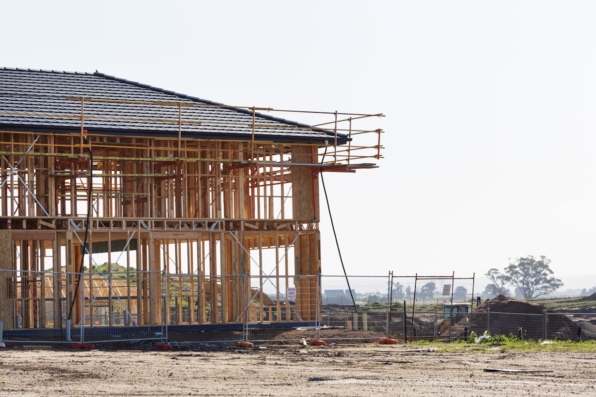 Custom home under construction on a dirt lot in the Central Valley, framing and roof complete