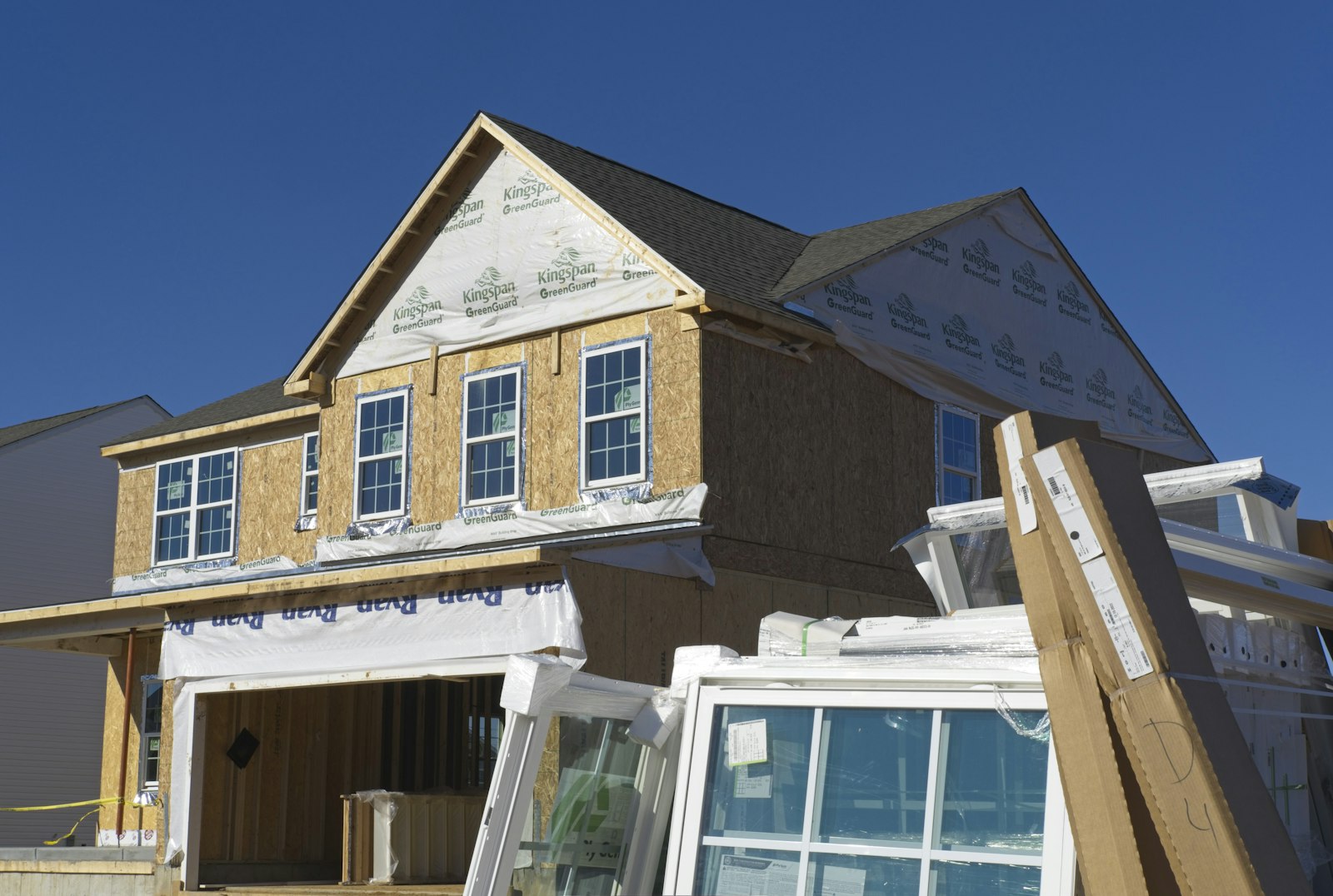 New two-story home under construction with house wrap and window installation on a Central Valley lot, representing ADU and multi-family construction in Riverbank, California
