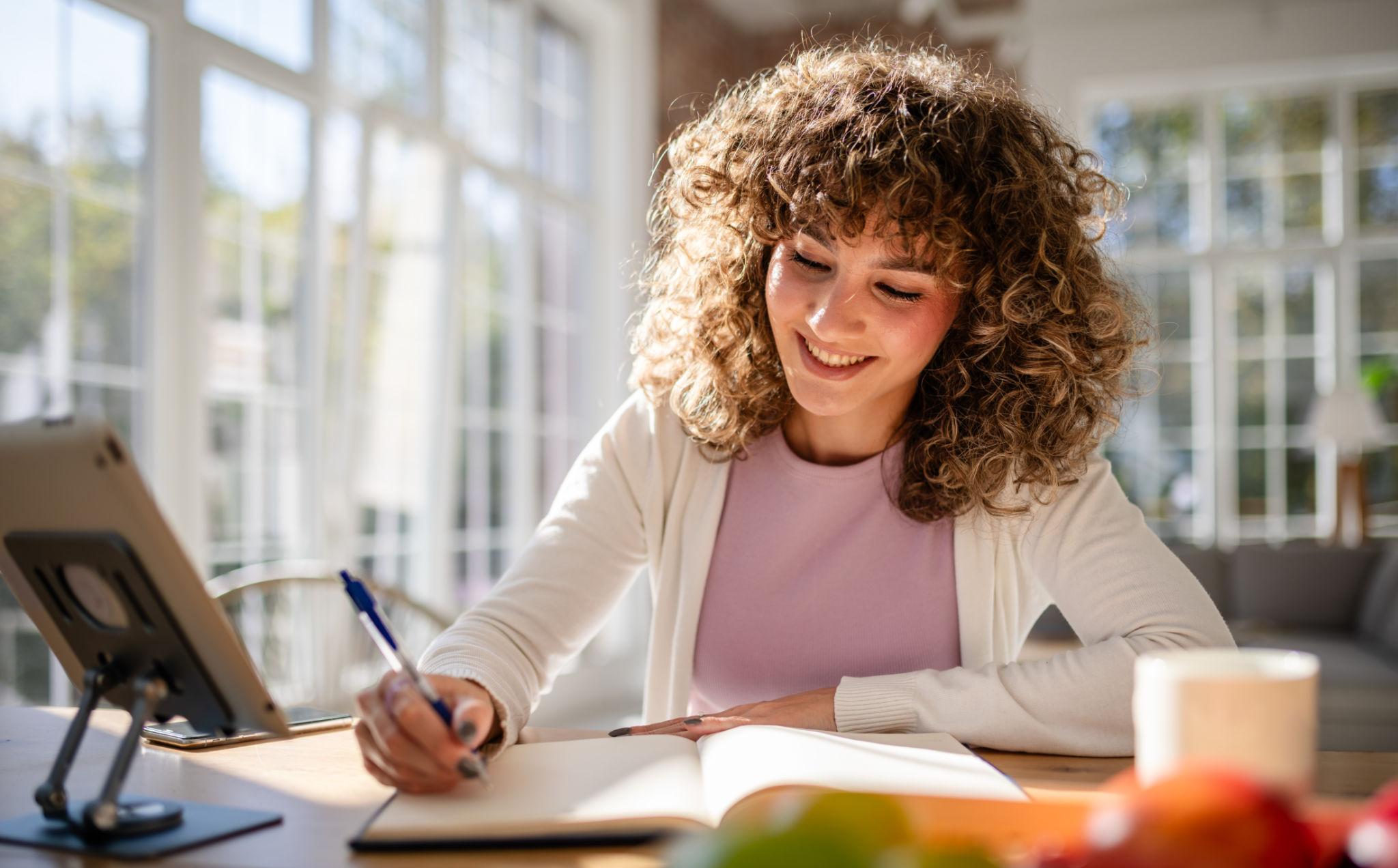 woman journaling with windows and sunlight in the background