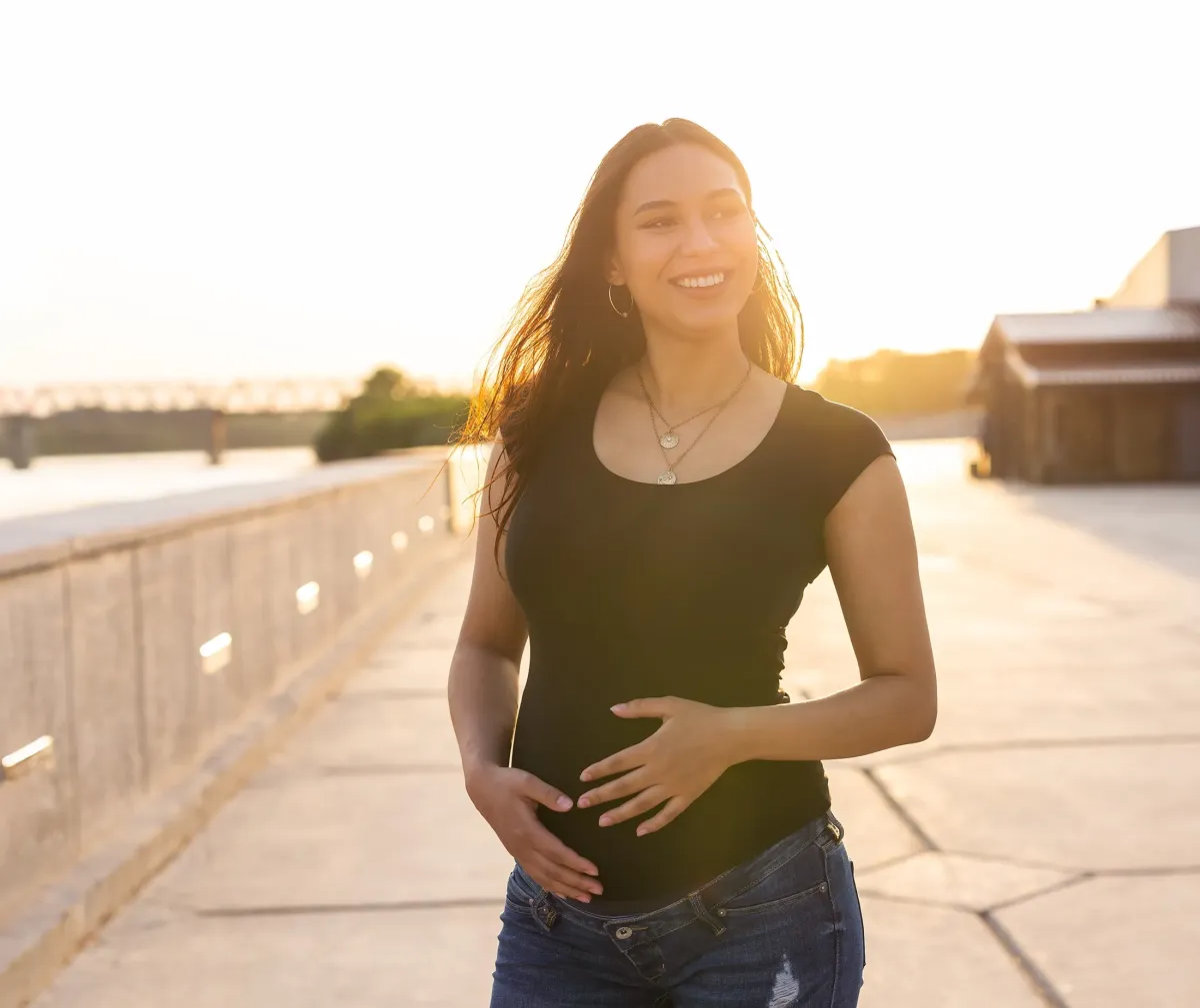 smiling pregnant woman with sunlight in the background