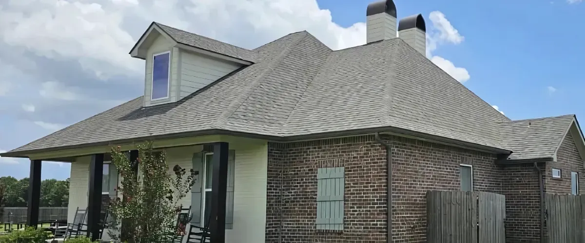 Well-kept brick home featuring clean shingles, siding, and manicured landscaping.
