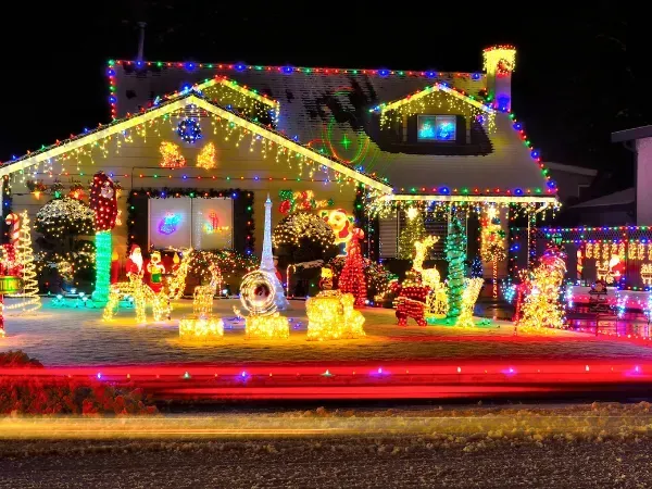House fully decorated with vibrant multicolor Christmas lights and festive yard figures.