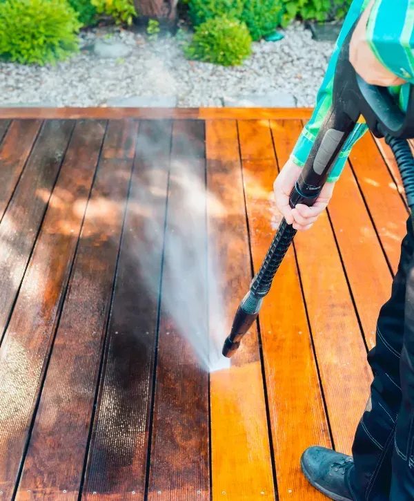 Pressure washer cleaning a dirty wooden deck surface.