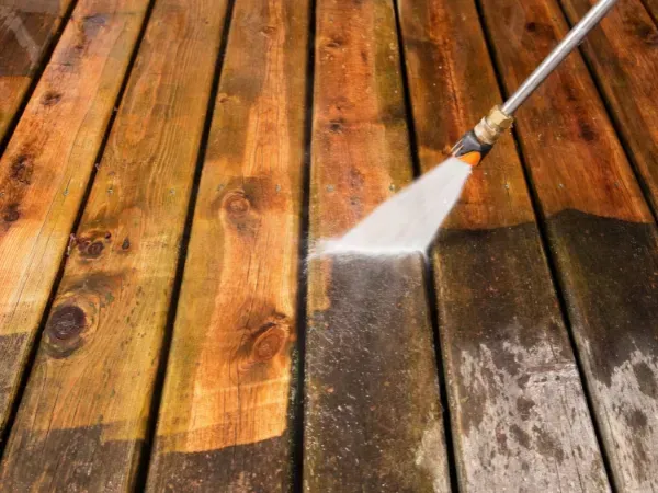  Pressure washer cleaning a dirty wooden deck surface.