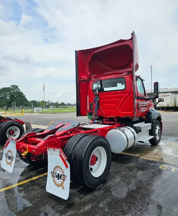 Red semi-truck tractor parked on wet pavement after exterior detailing