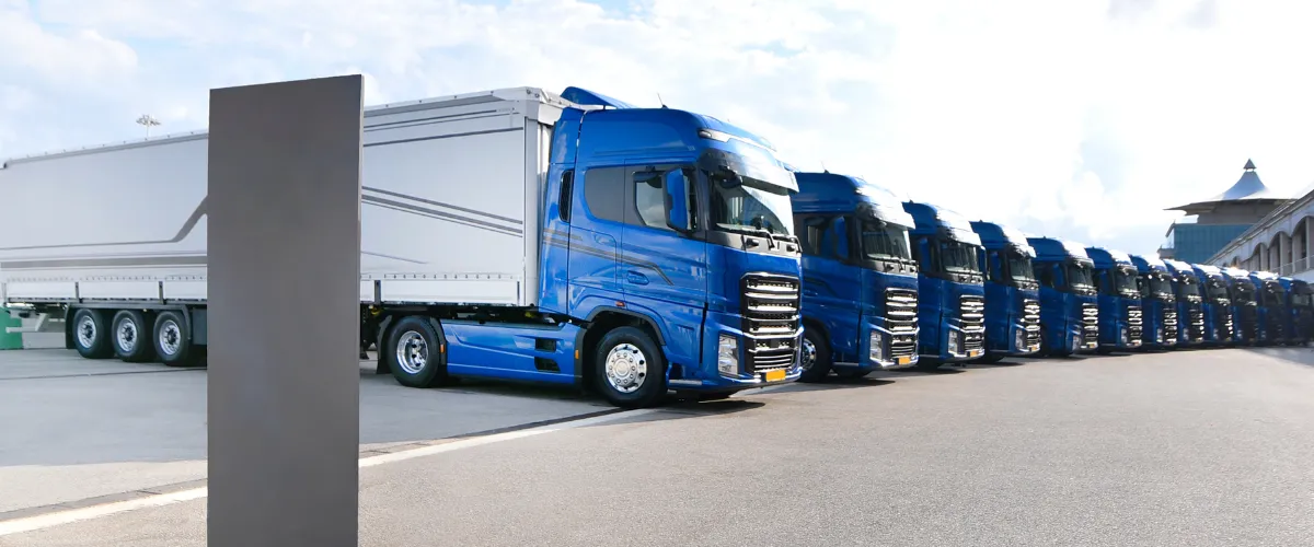  Row of shiny blue semi-trucks parked in a clean logistics or distribution yard
