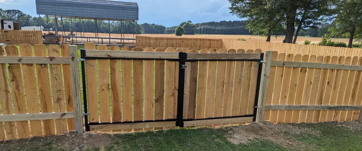 Wooden privacy fence with a double gate and reinforced black metal frame.