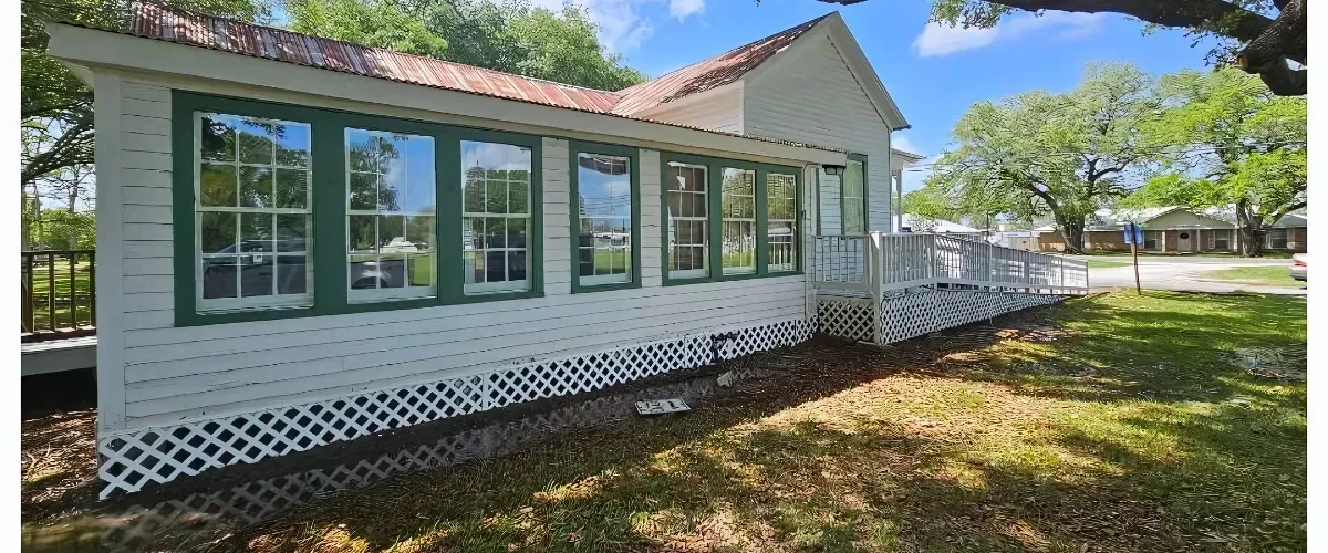  Historic white house with green window trim and a wheelchair-accessible ramp.