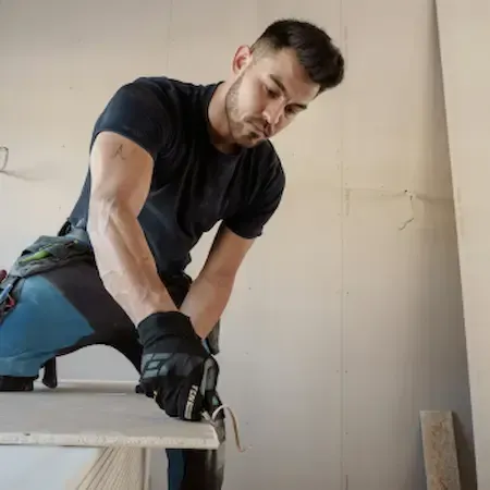 Worker installing cabinetry with jigsaw and measuring tools, highlighting home improvement and carpentry service.