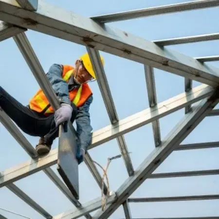 Worker securing metal roof framing with safety harness, showing structural carpentry and repair skills.