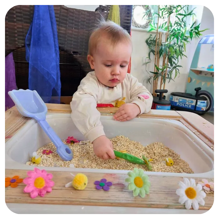 Infant playing in sandbox sensory play