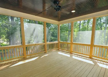 Enclosed screened porch with wood railings and natural lighting