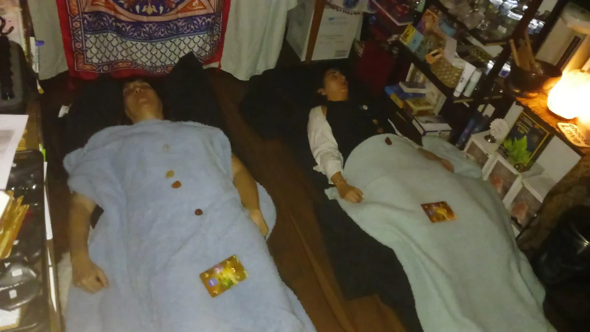 2 people laying on yoga mat in a calm setting receiving a sound bath