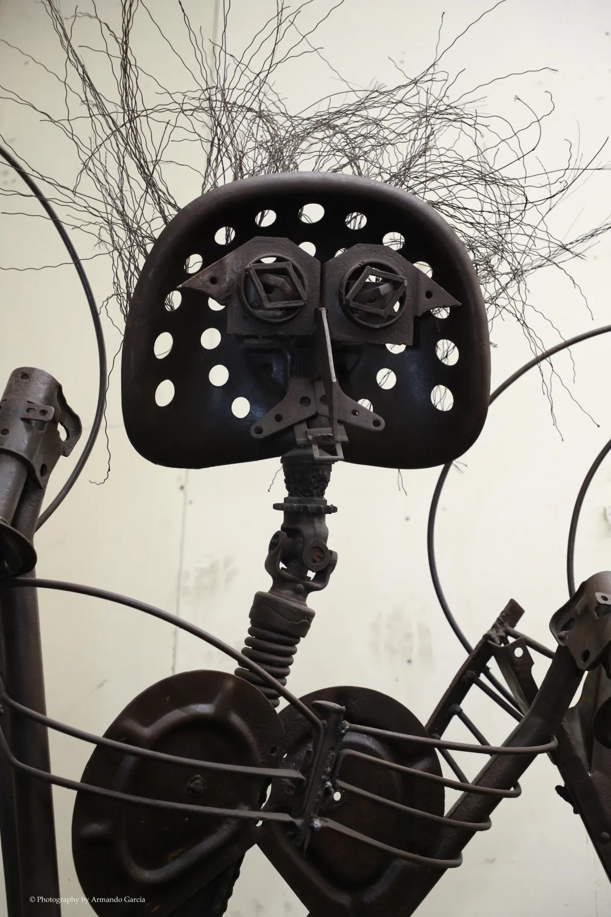 found object welded sculpture with a tractor seat for a face and various other tractor materials arranged to create this mythical creature