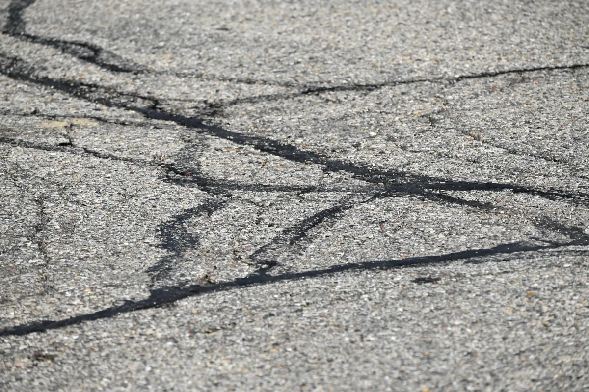 Close-up of asphalt crack filling sealing pavement cracks with hot rubberized crack filler