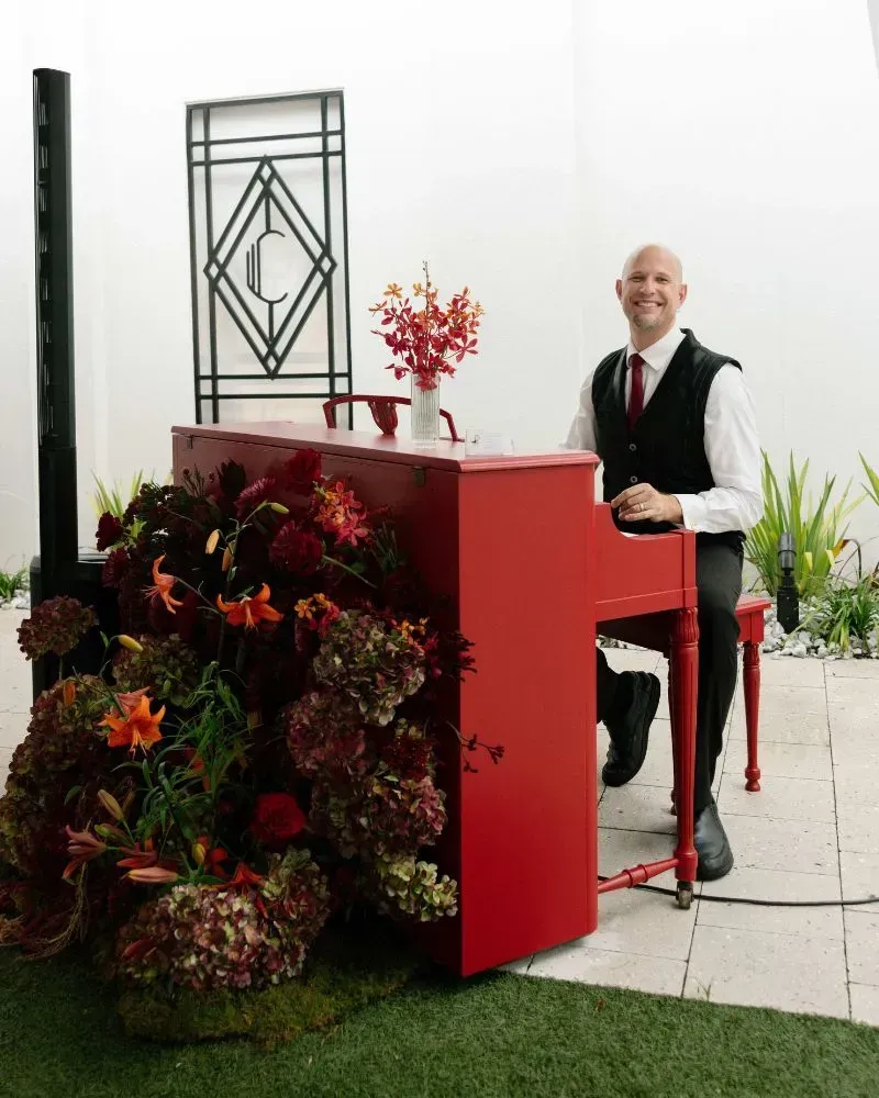 Jeremy Weinglass playing a red piano for the Jax Bridal Fashion Show at the Clay Theater