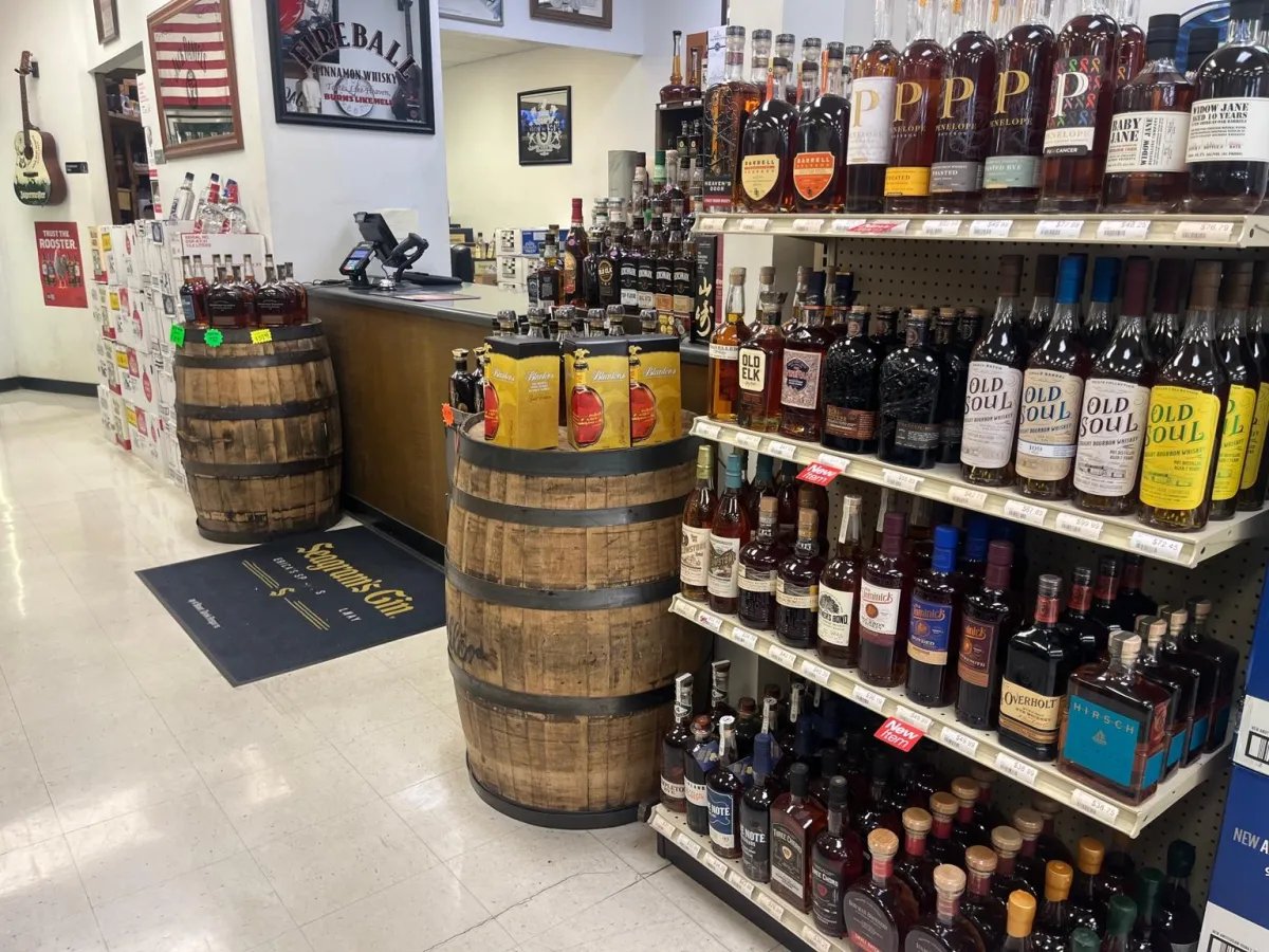 Lifestyle shot of staff arranging craft spirits on a shelf with warm interior lighting.