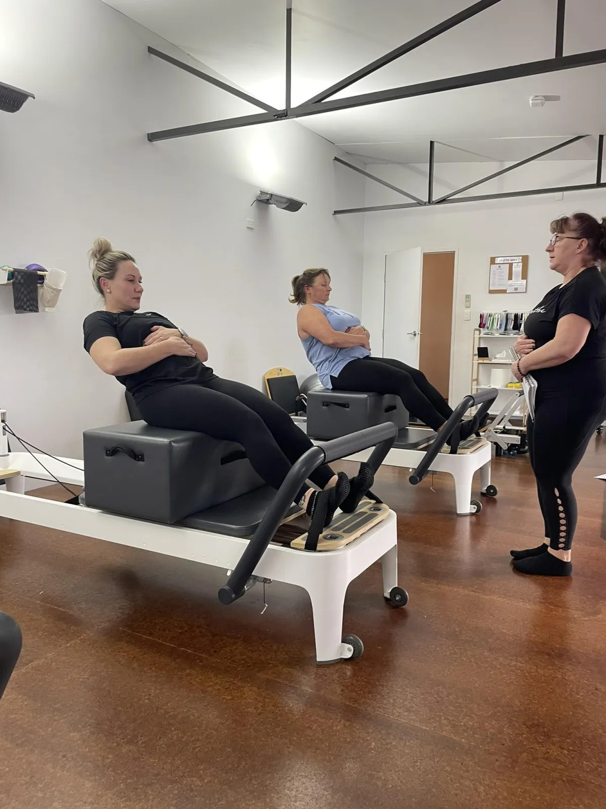 Pilates instructor guiding students through movement training in a supportive studio environment.
