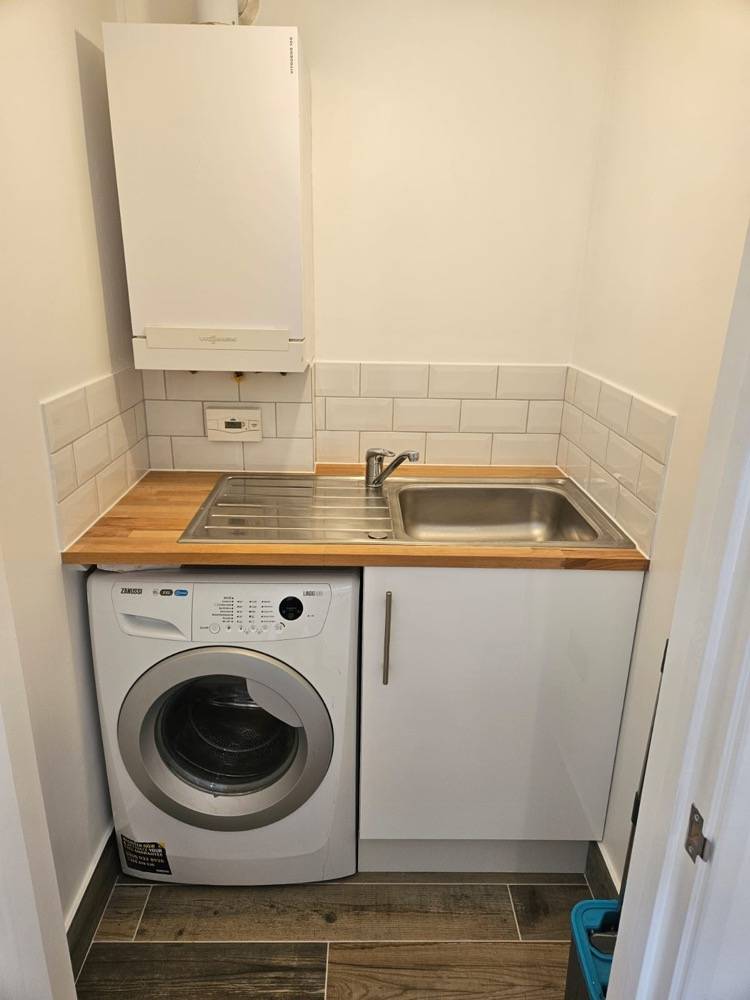 Compact utility room with washing machine, sink and boiler by DR Construction