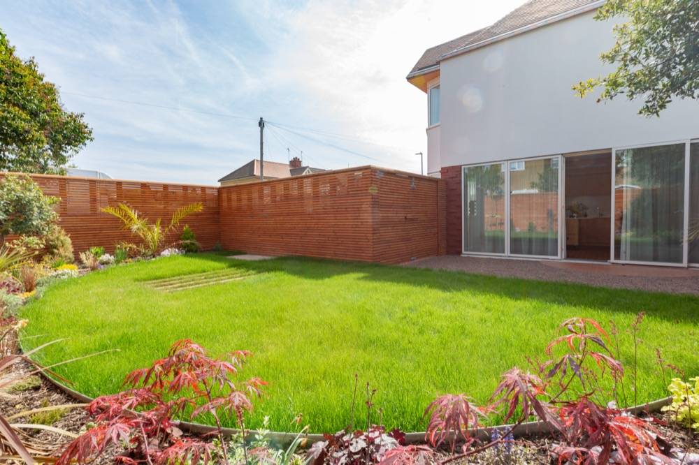 Rear garden of new build family home with timber fencing and rendered facade