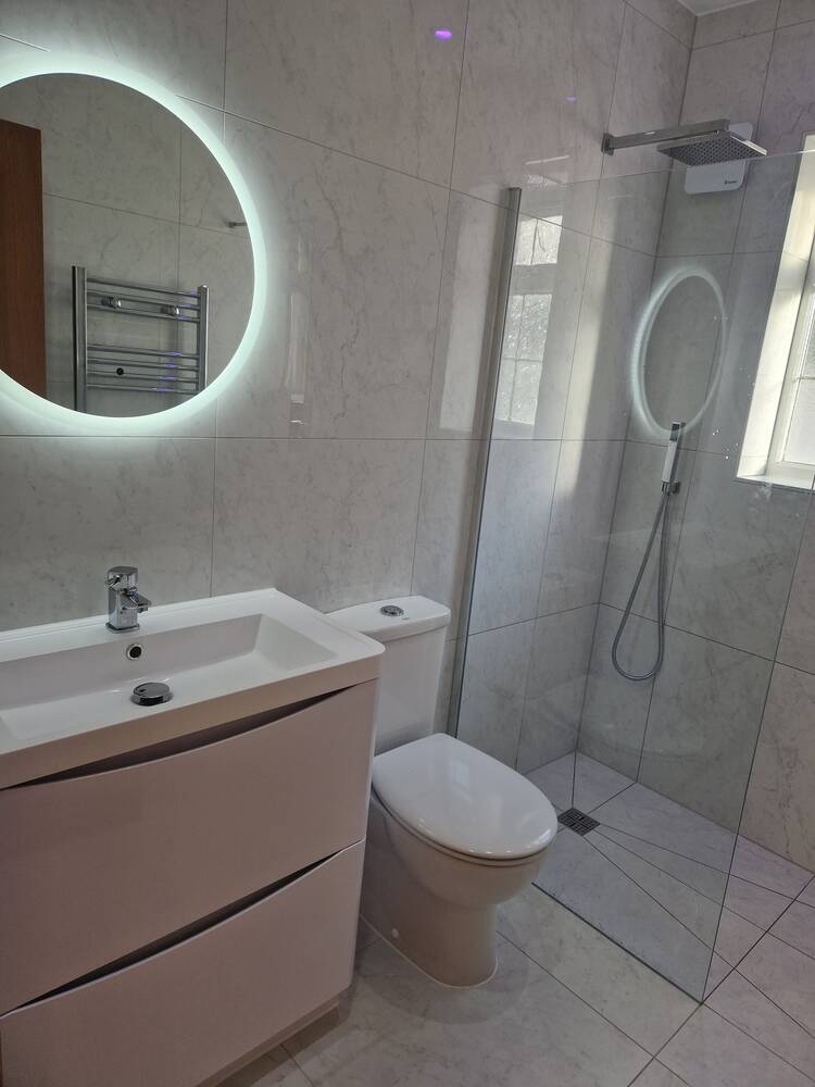 Walk-in shower room with round LED mirror and vanity, converted from a bathtub by DR Construction