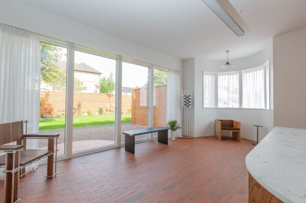 Open-plan living area in new build with sliding glass doors and terracotta tile floor