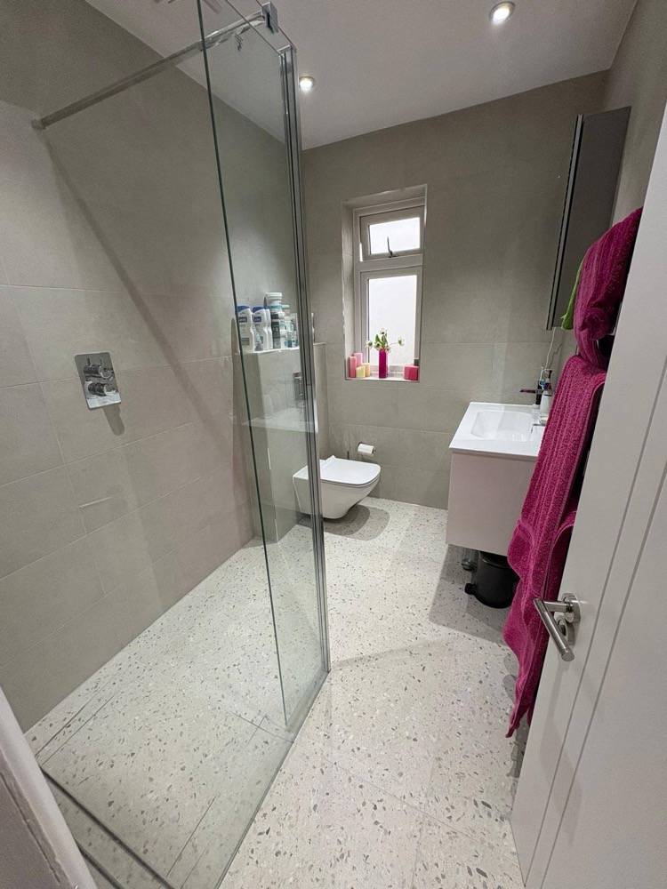Grey wet-room style bathroom with full-height glass screen by DR Construction
