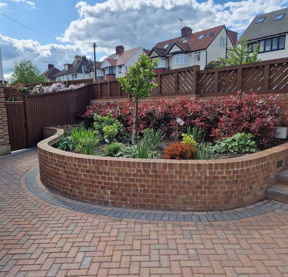 Curved brick garden wall with block paving and raised flower bed by DR Construction