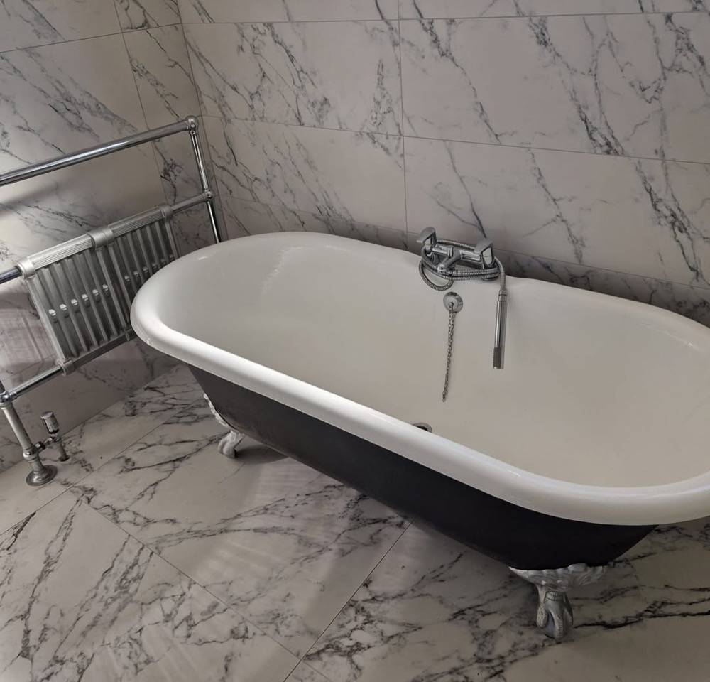Black freestanding claw-foot bath against marble walls in luxury bathroom