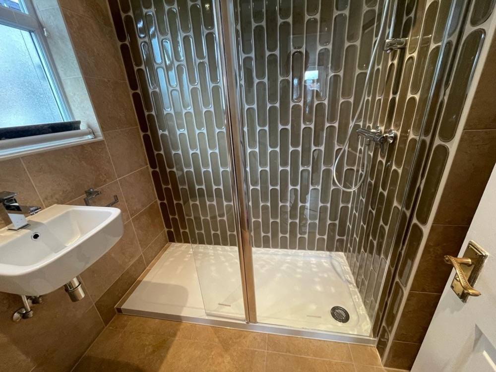 Walk-in shower enclosure in brown-tiled traditional bathroom by DR Construction