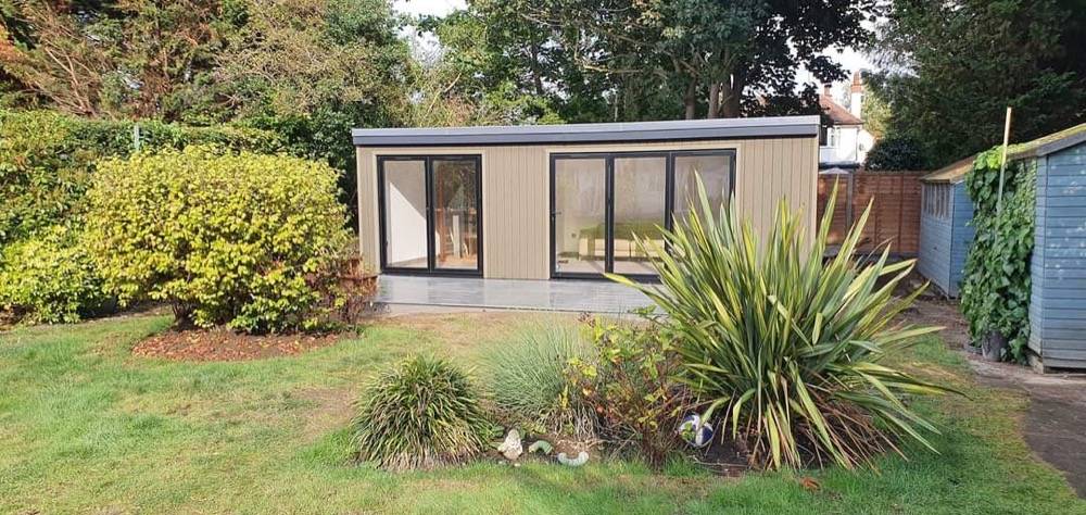 Exterior of a bespoke garden room with grey cladding and landscaped lawn