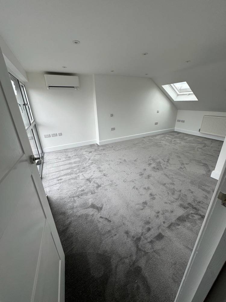 Finished loft conversion bedroom with grey carpet, Velux skylight and air conditioning