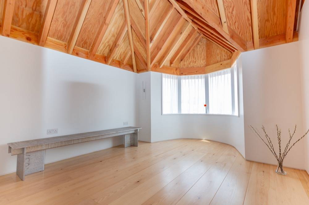 Upstairs room in new build with exposed timber A-frame roof structure and bay window